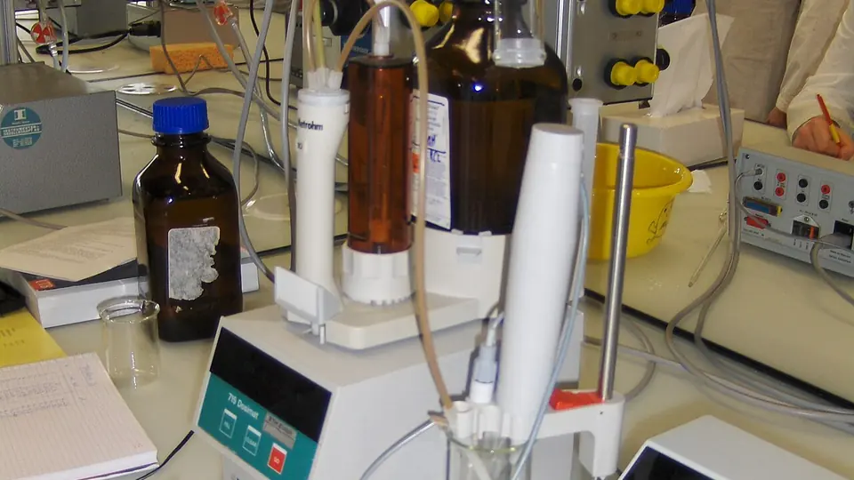 Medidor de pH e frascos de reagente numa bancada de laboratório de análise