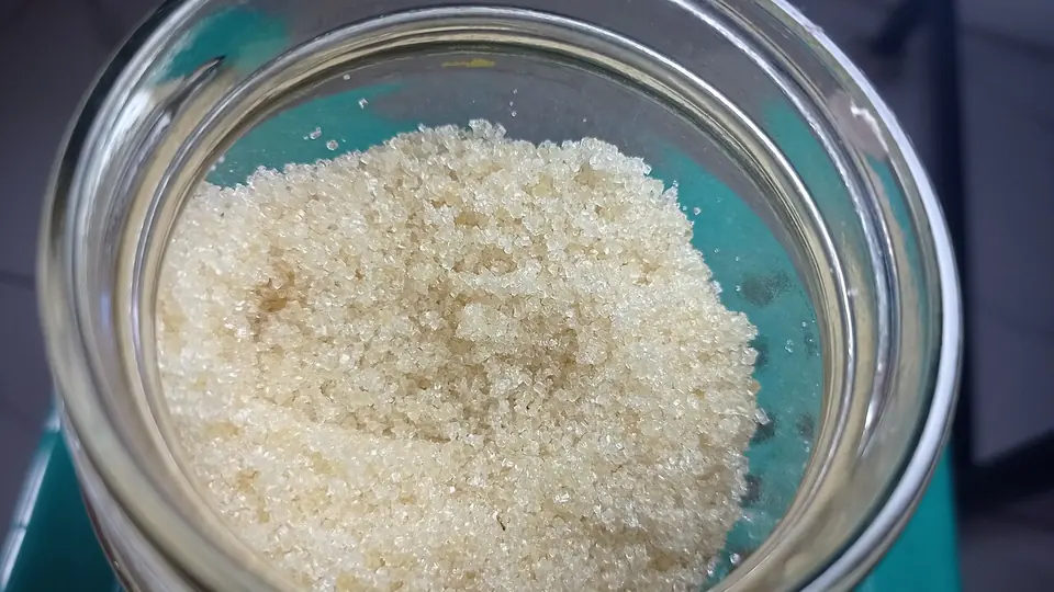 Açúcar cristal branco dentro de pote de vidro aberto sobre a mesa