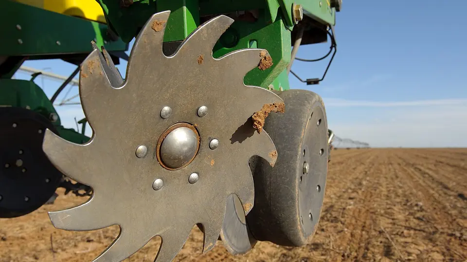 Disco recortado de grade agrícola em primeiro plano sobre a lavoura preparada