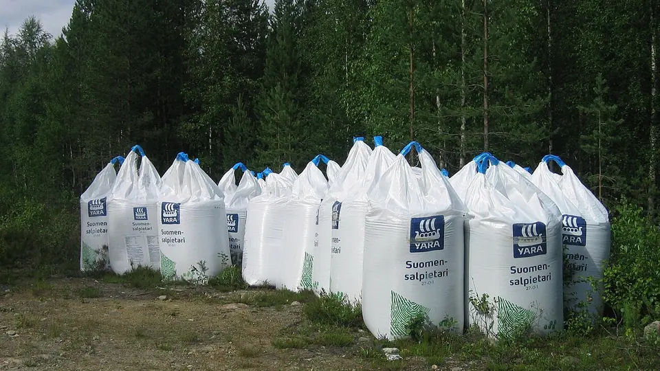 Big bags de fertilizante enfileirados em clareira com mata ao fundo