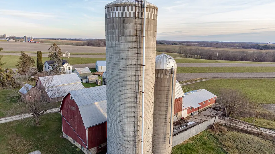 Silos altos e galpões de uma fazenda vistos do alto, cercados por talhões