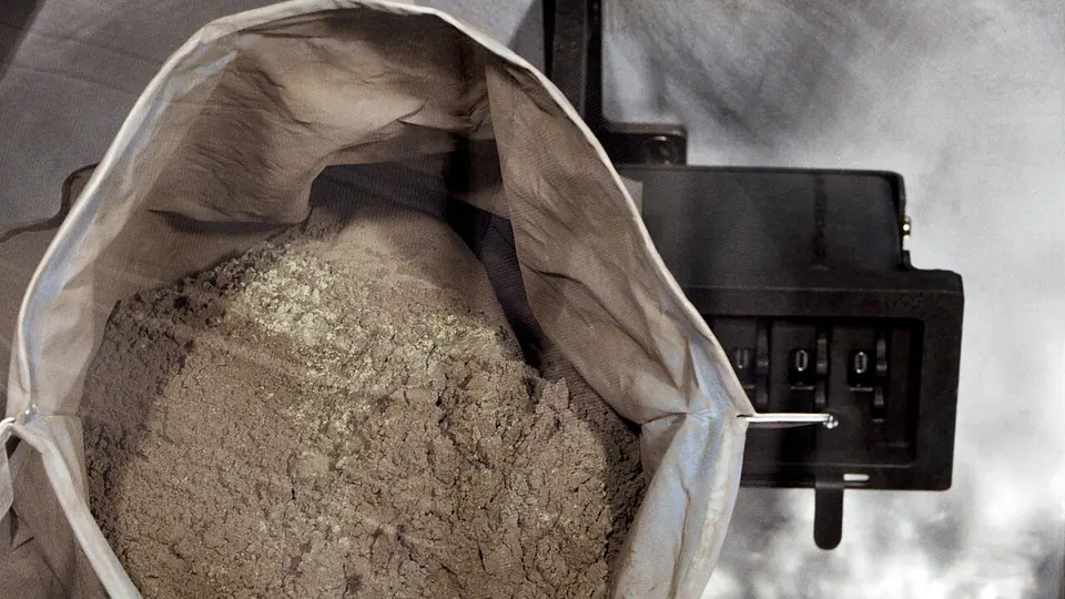 Saco grande aberto cheio de pó mineral fino e acinzentado, com textura de material moído
