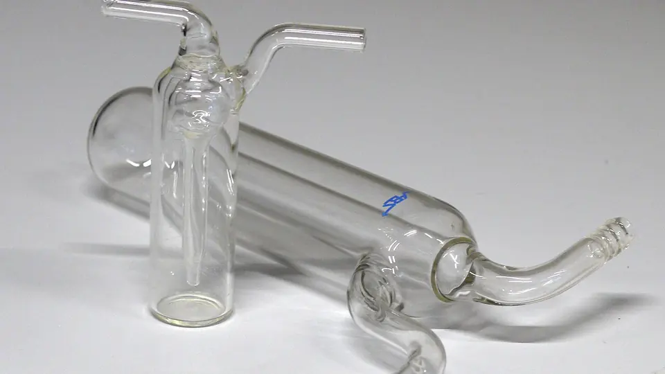 Aparelho de vidro de laboratório com tubos curvos sobre bancada clara