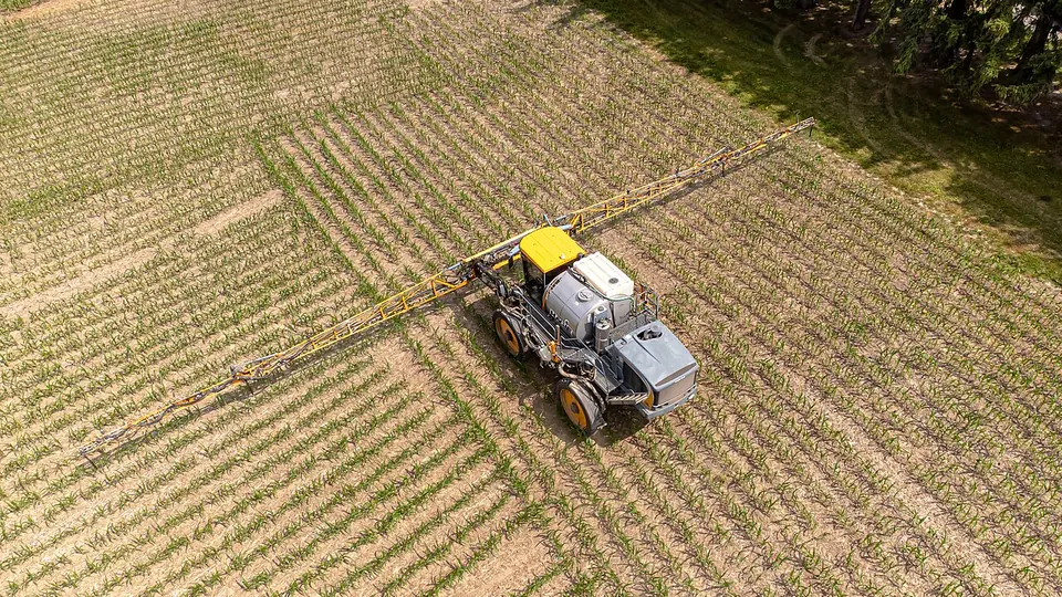 Máquina agrícola espalhando fertilizante sobre a lavoura verde