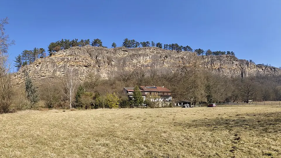 Paredão de rocha calcária clara acima de um campo aberto sob céu limpo