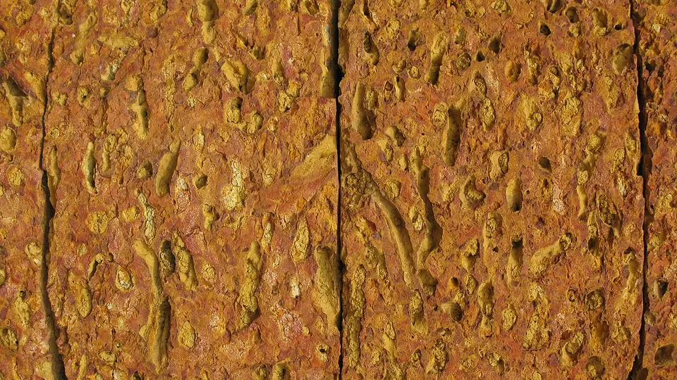 Paredão de laterita endurecida com textura porosa e cor alaranjada