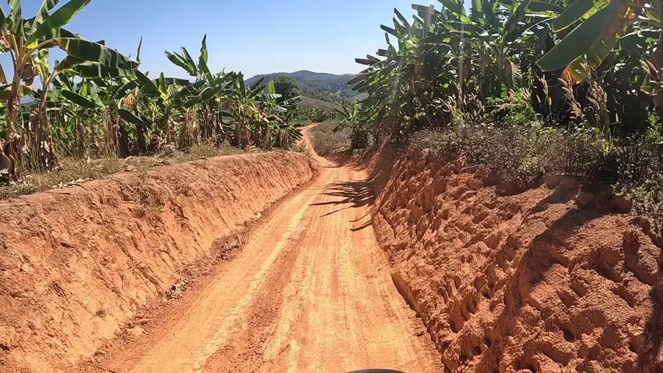 Corte de barranco de solo vermelho exposto na beira de uma estrada de terra