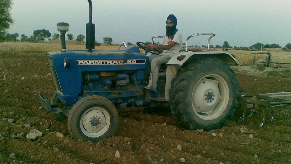 Trator em operacao na lavoura, com o campo verde ao fundo
